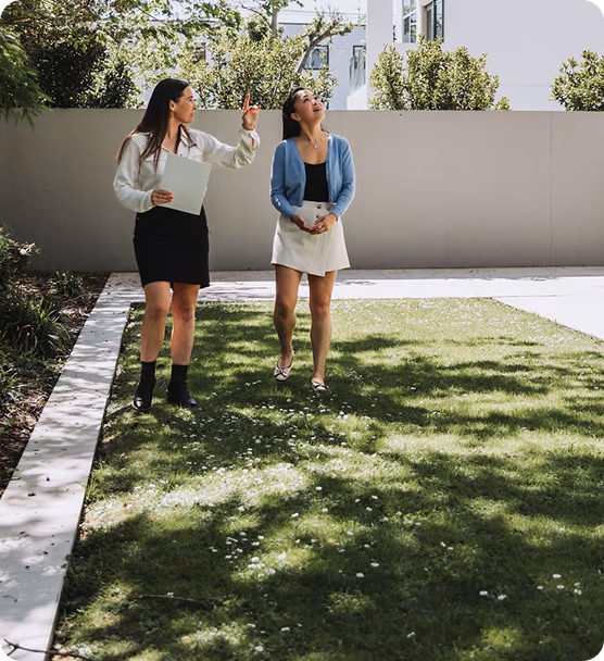 Two colleagues talking outdoors beside a property